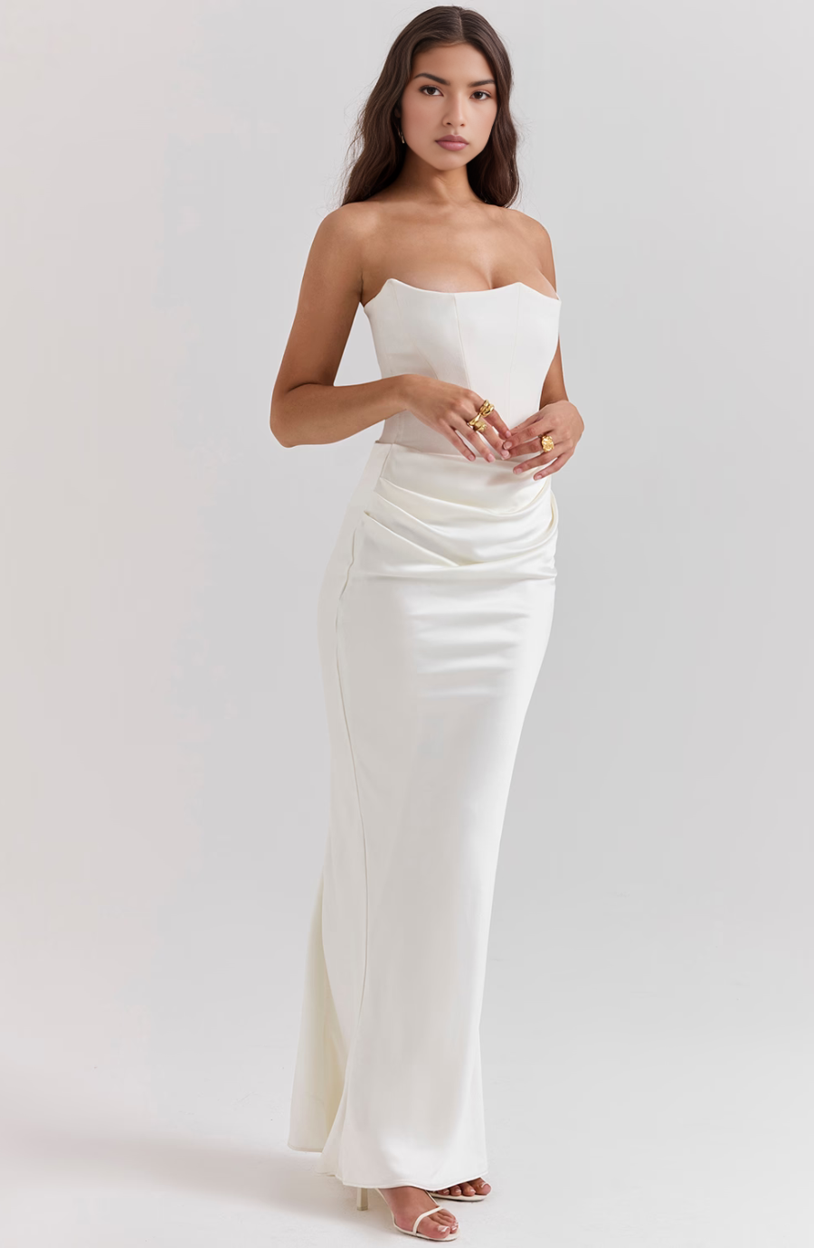 Woman wearing a strapless white evening gown on a plain background
