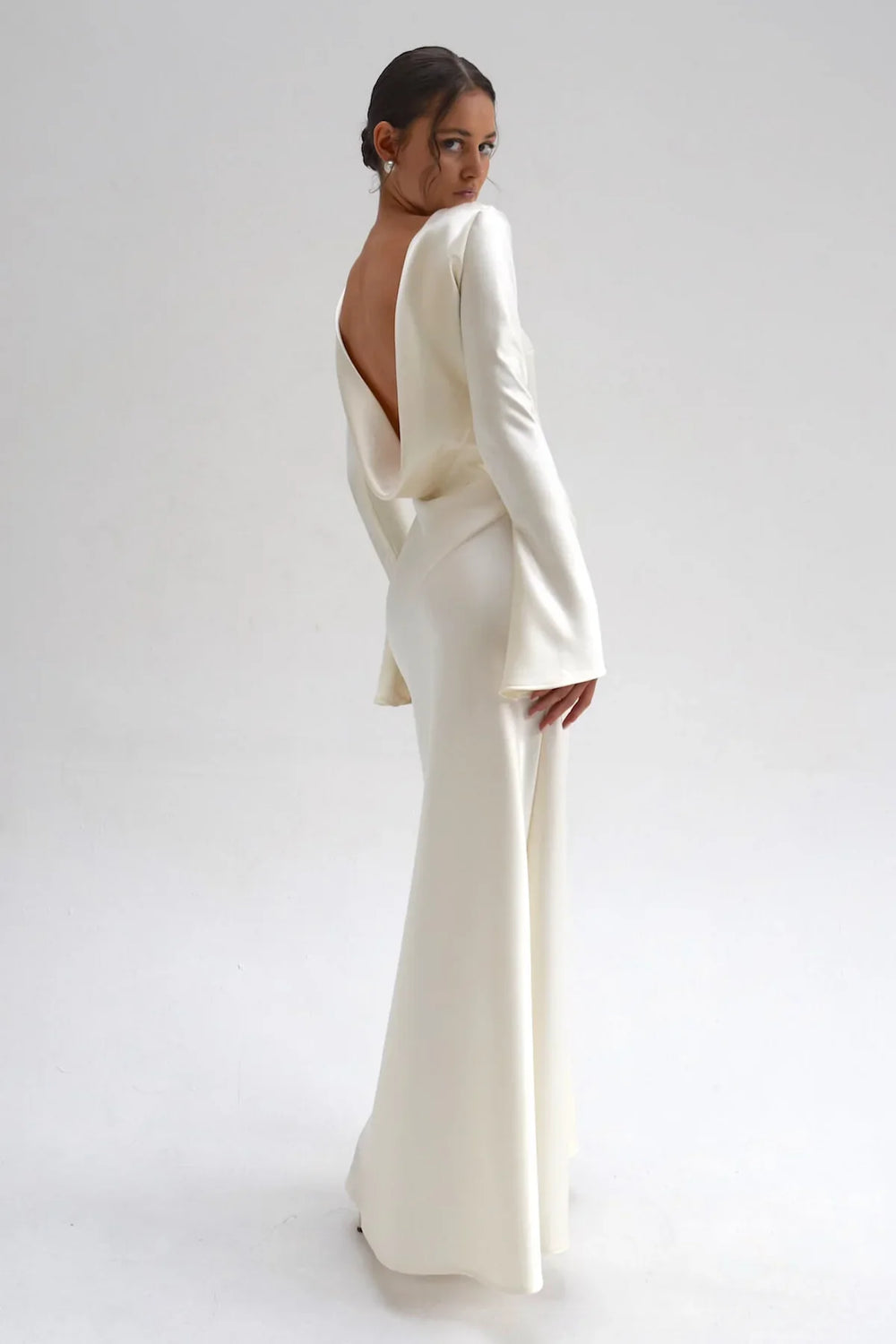 Woman wearing a white evening gown with a plunging neckline on a plain background