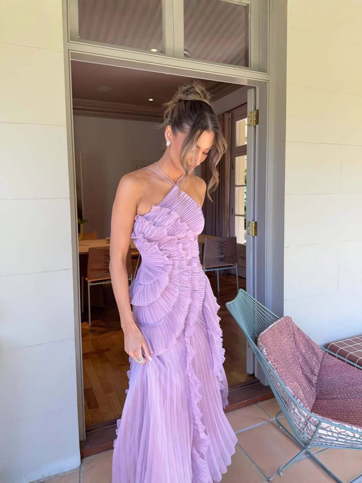 Woman in a lavender one-shoulder dress standing in a doorway.