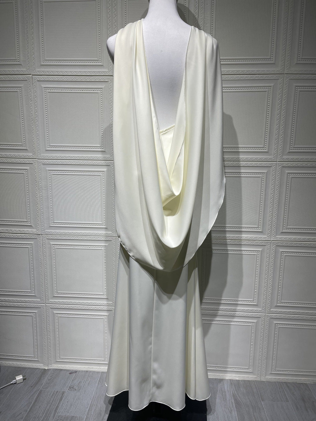 White dress on a mannequin against a gray paneled wall