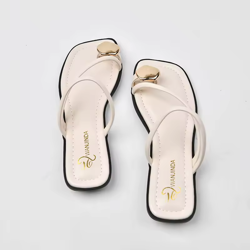 Pair of white sandals with gold accents on a light gray background