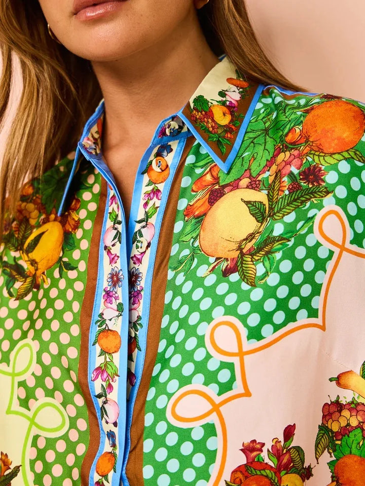 Close-up of a person wearing a colorful patterned shirt with fruit and polka dot designs.