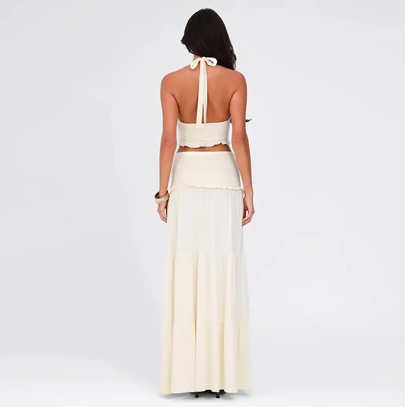 Woman wearing a white halter top and long skirt set on a light gray background