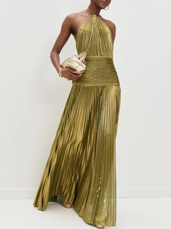 Woman wearing a gold pleated dress holding a matching clutch against a white background