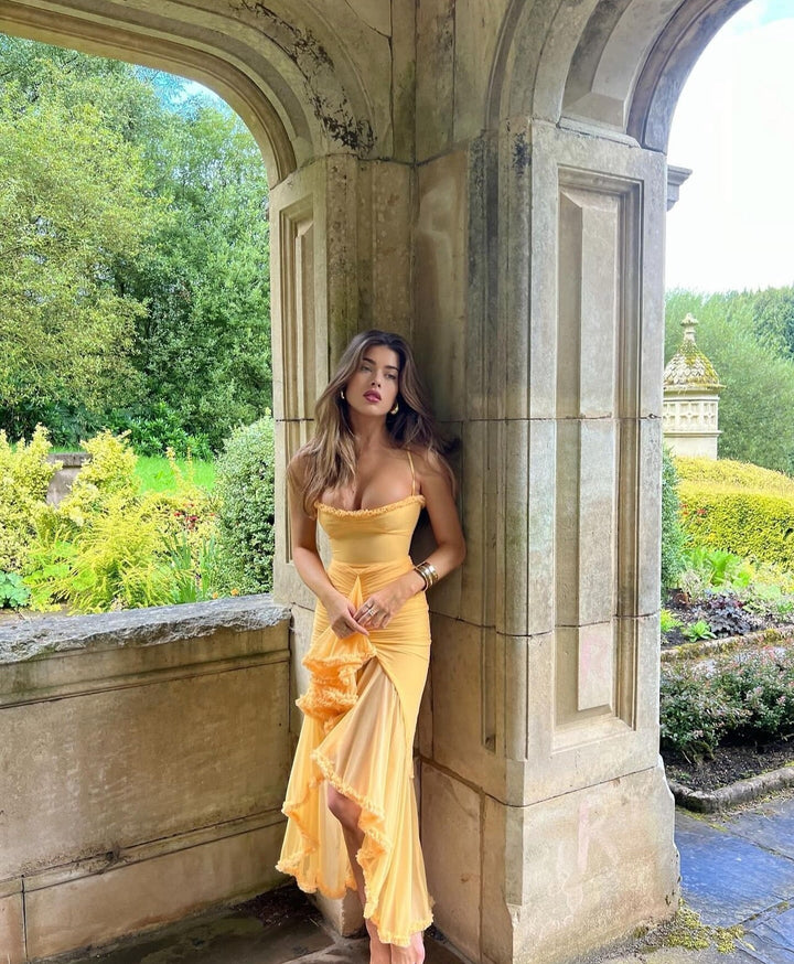 Woman in a yellow dress standing in an archway with garden scenery