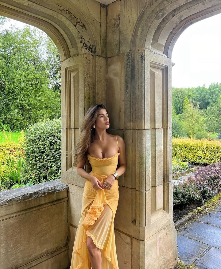Woman in a yellow dress standing in an archway with greenery around