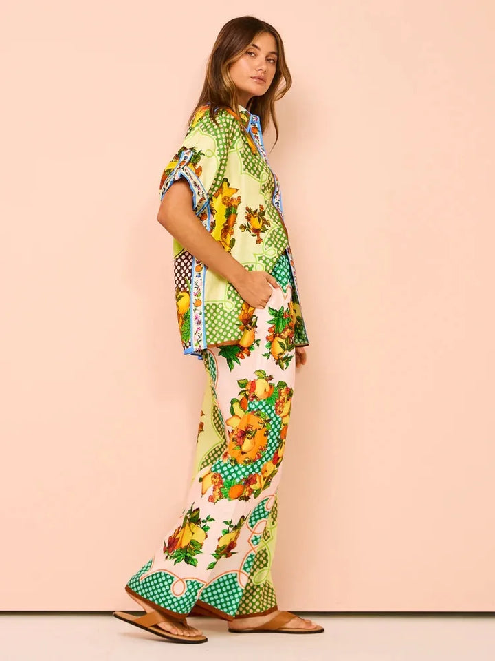 Woman wearing a colorful outfit with floral and geometric patterns on a pink background