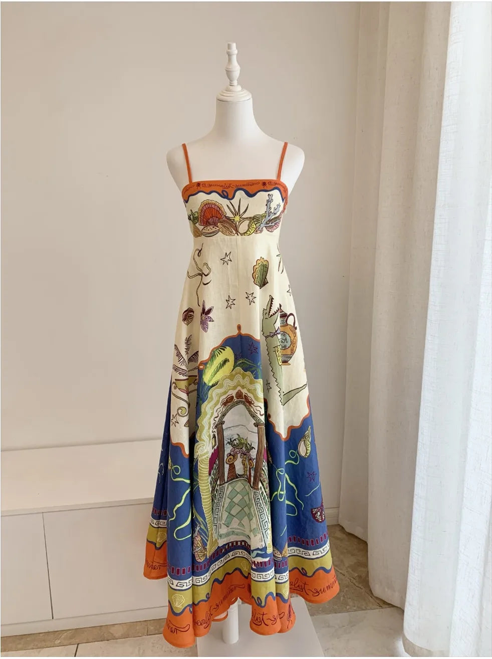 Colorful dress with intricate patterns on a mannequin against a neutral background