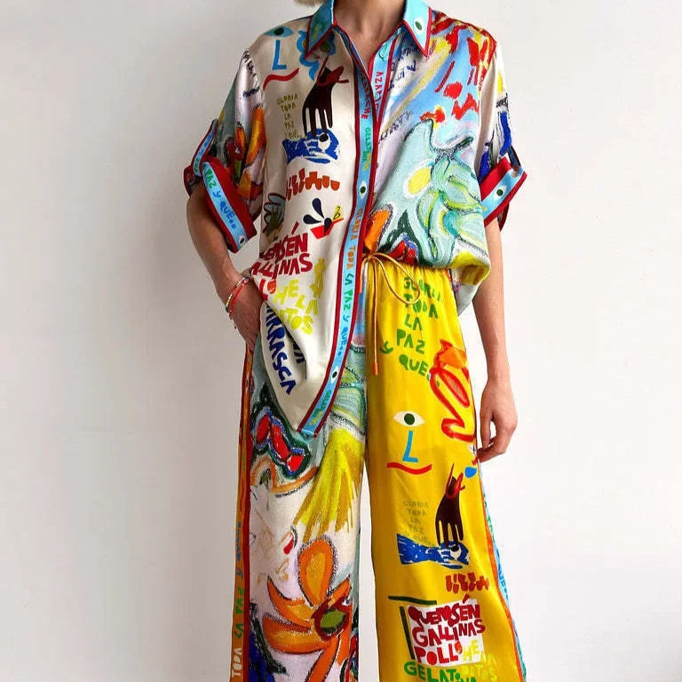 Person wearing a colorful outfit with a patterned shirt and yellow pants on a plain background