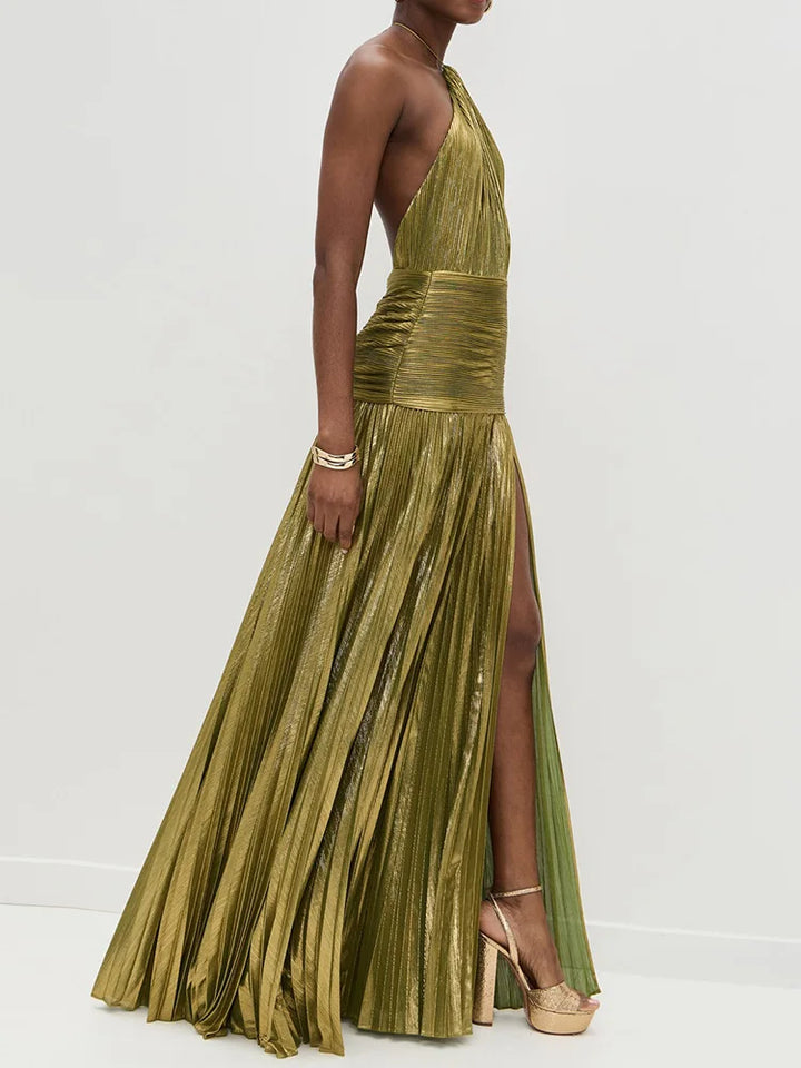 Woman wearing a gold pleated dress with a slit on a white background