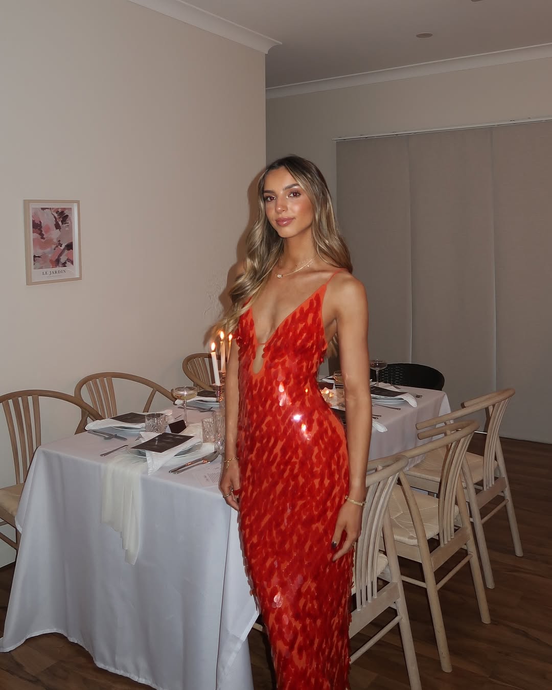 Woman in a red dress standing in a dining room with tables and chairs.