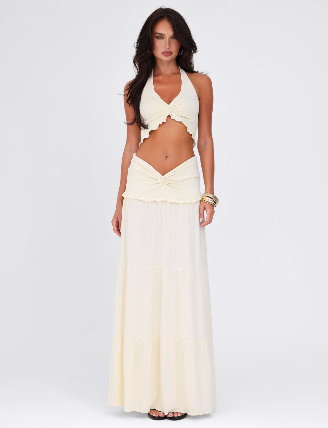 Woman wearing a white halter top and long skirt on a white background