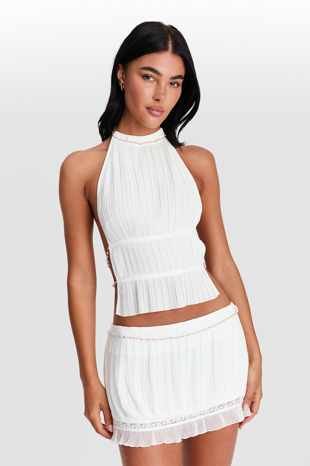 Woman wearing a white ribbed halter top and skirt set on a plain background