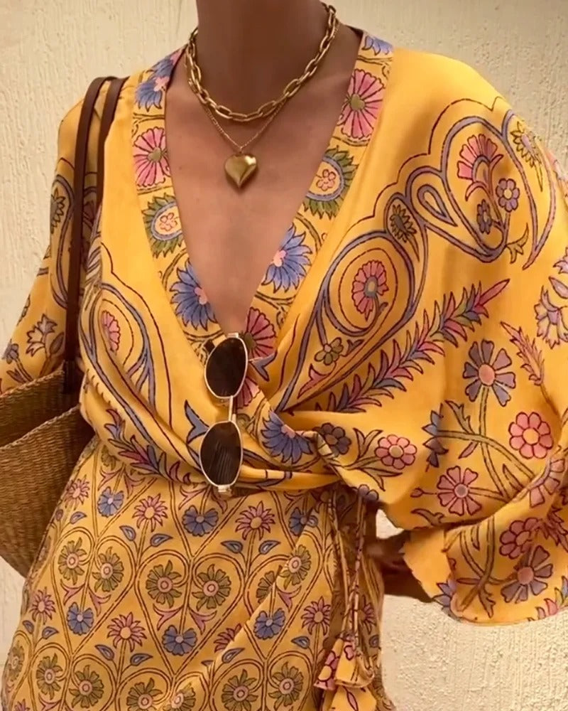 Person wearing a yellow patterned outfit with sunglasses and a bag.
