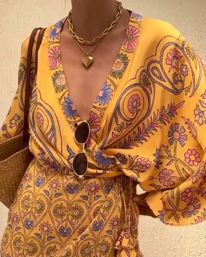 Person wearing a yellow patterned outfit with sunglasses and a bag.