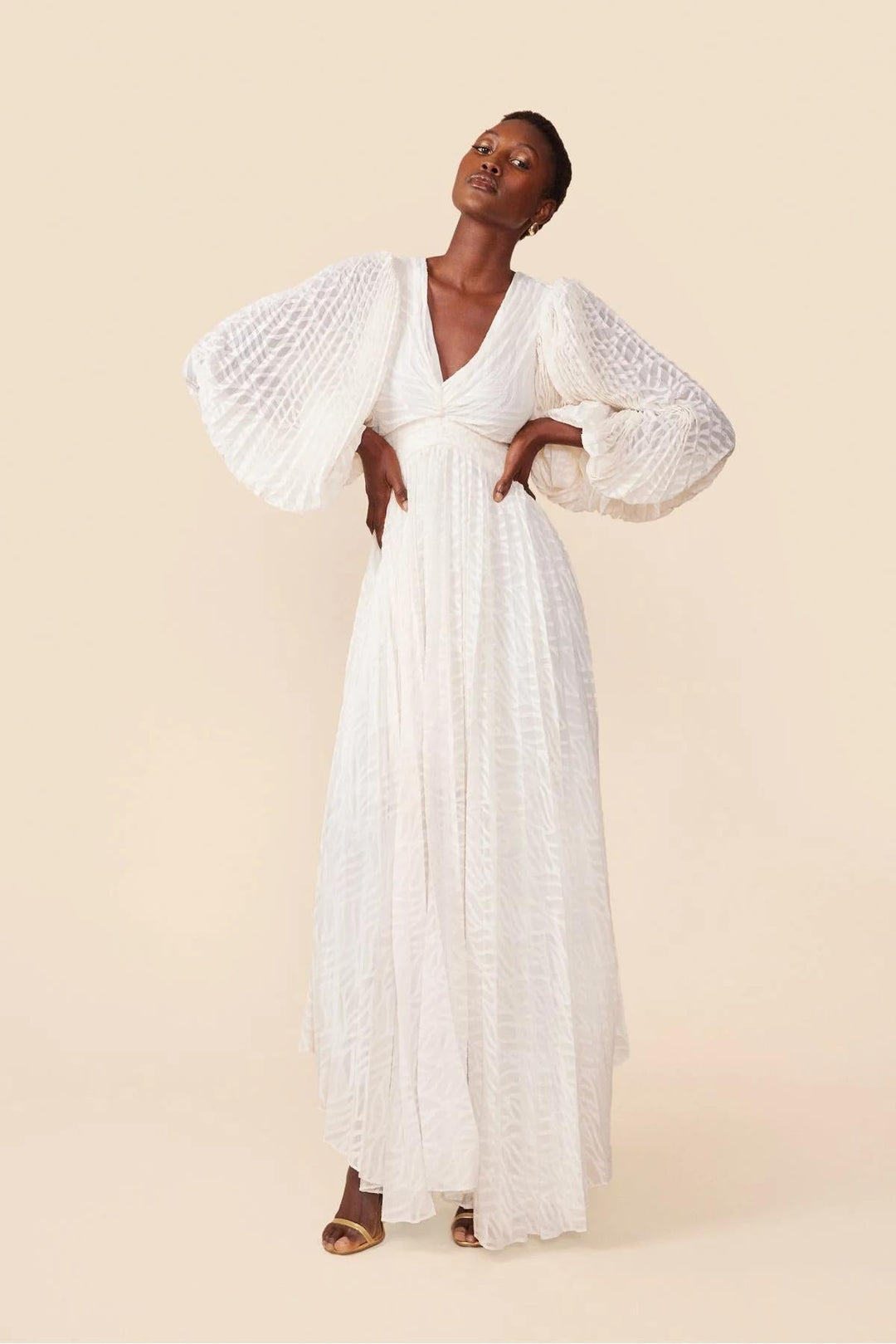 Woman wearing a white dress with textured sleeves on a beige background