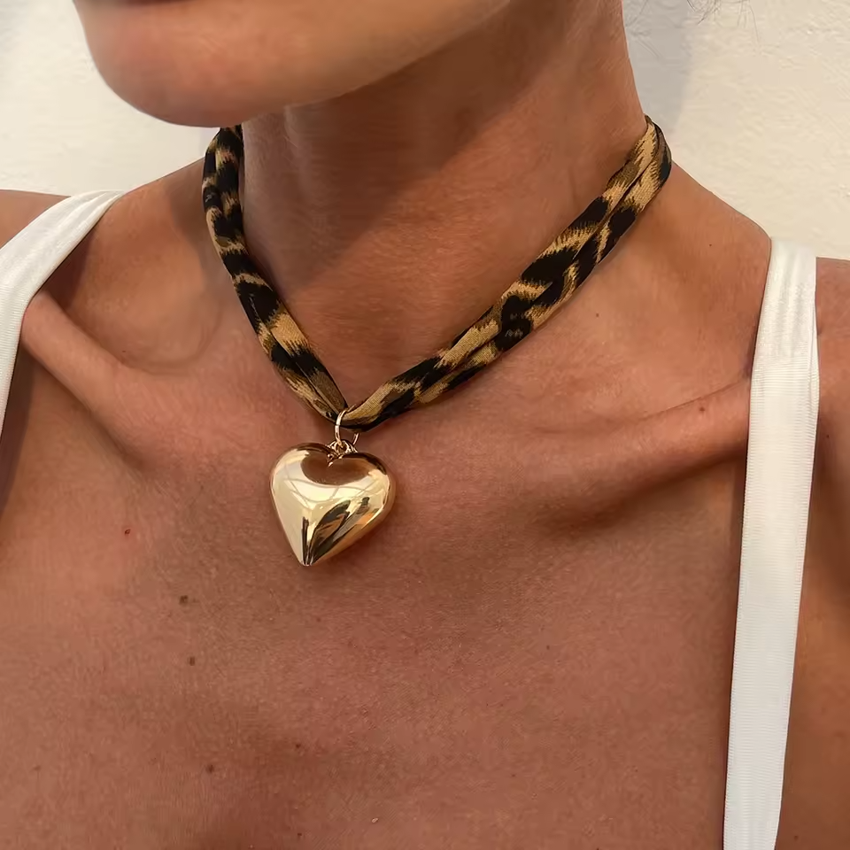 Leopard print necklace with a gold heart pendant worn by a person.