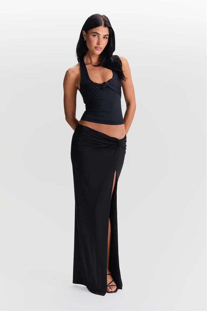 Woman wearing a black sleeveless top and long black skirt on a white background