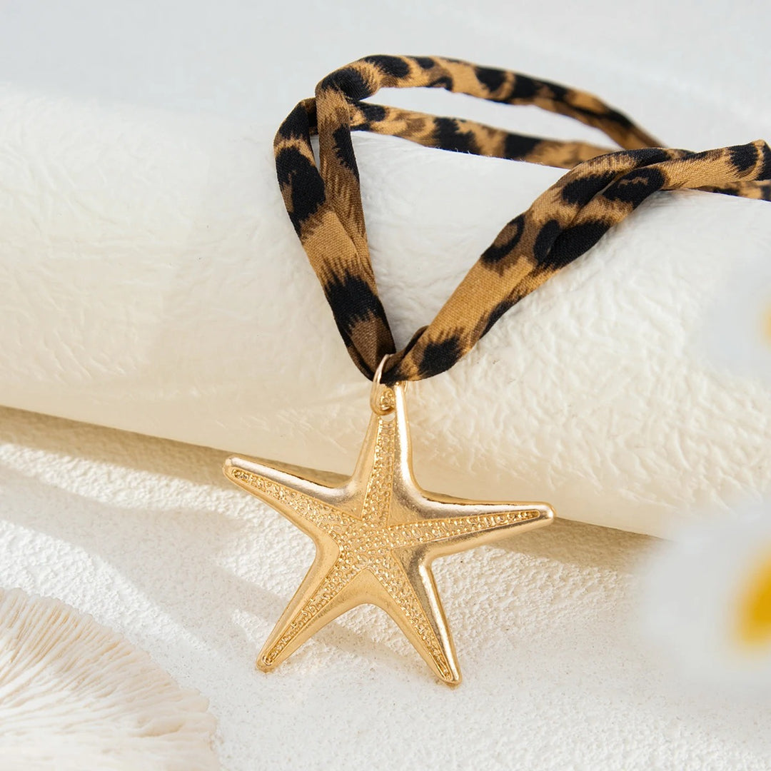 Gold starfish pendant on a leopard print cord against a white background