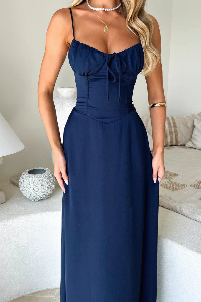 Woman wearing a navy blue dress in a bedroom setting