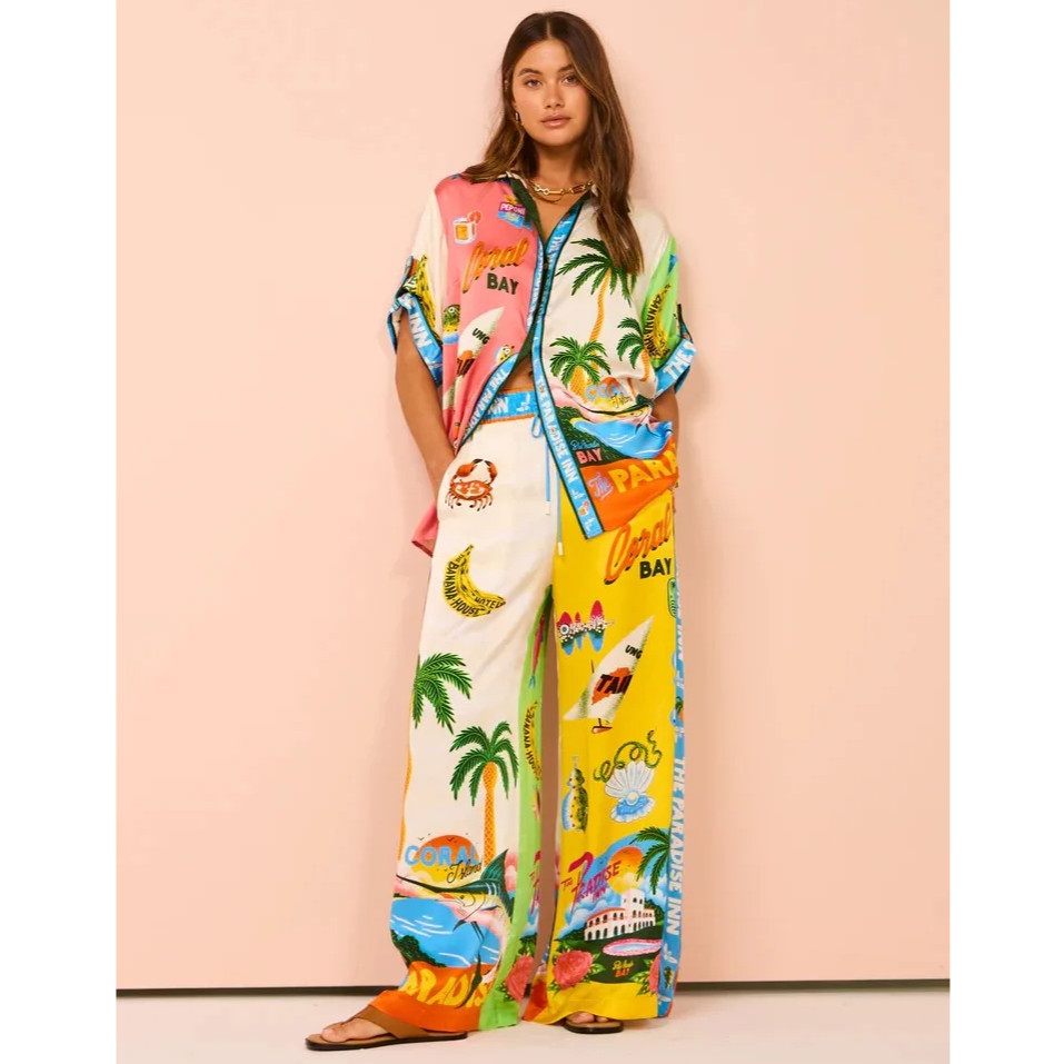 Woman wearing a colorful outfit with tropical-themed design against a pink background