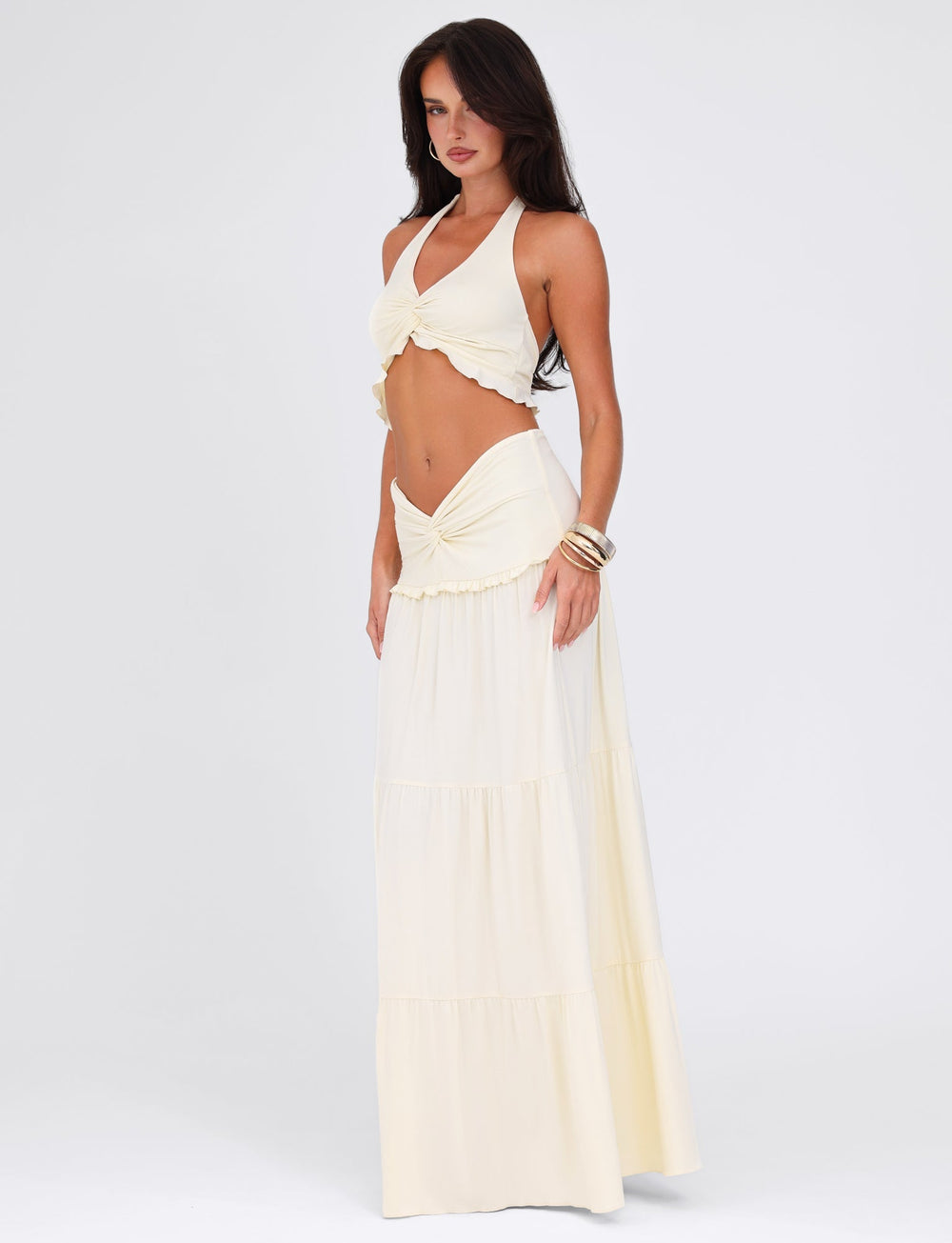 Woman wearing a white halter top and long skirt on a white background